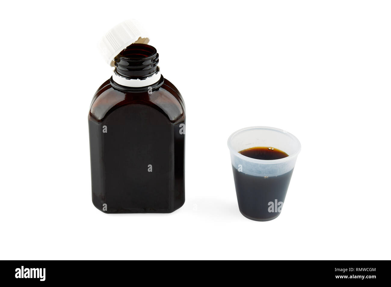 Bottle and small plastic glass with brown medicine. Isolated. Stock Photo