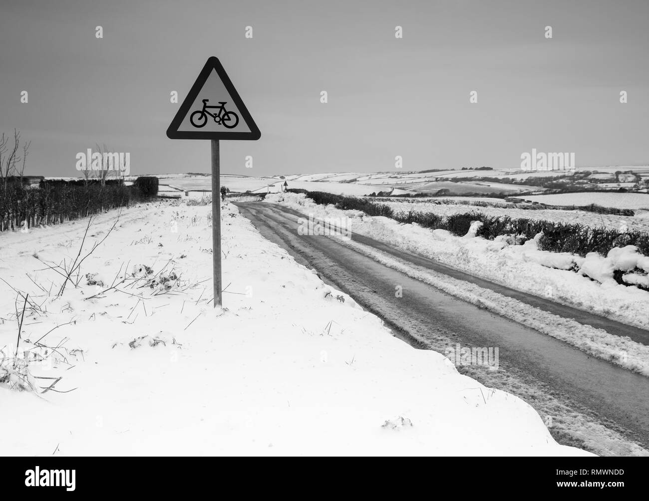 A bike lane sign standing by a snow ccovered roadside in Salcombe, Devon Stock Photo