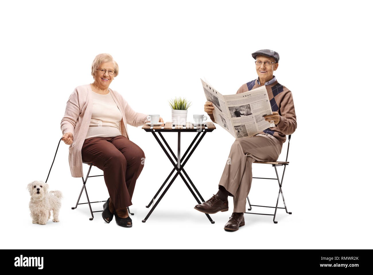 Senior couple sitting at a table with their dog and enjoying a cup of coffee isolated on white background Stock Photo