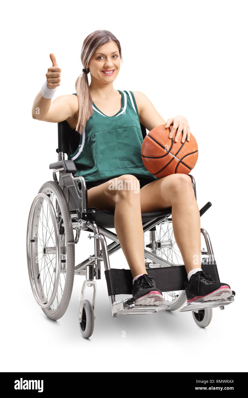 Young female athlete in a wheelchair holding basketball and showing thumbs up isolated on white background Stock Photo