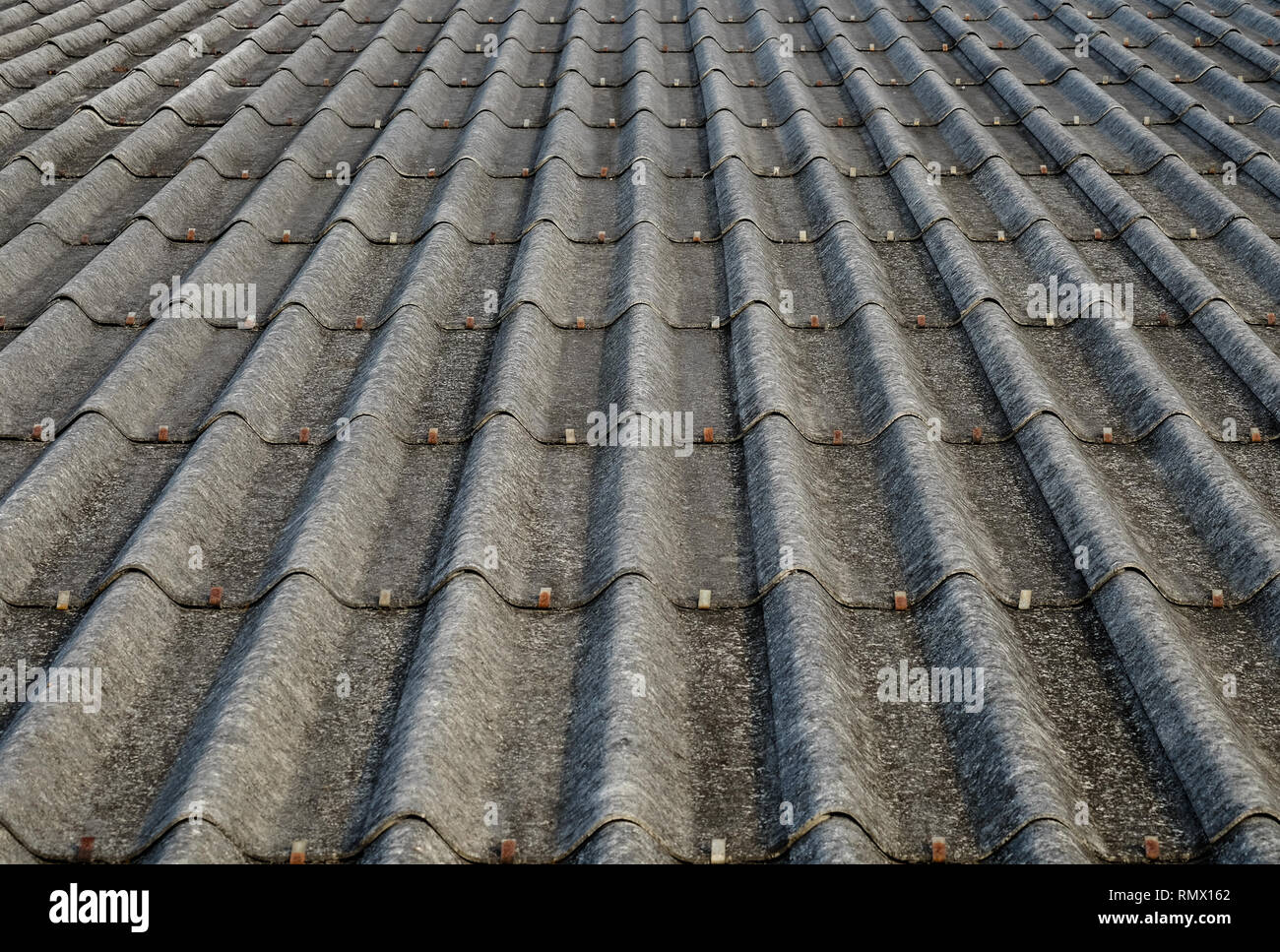 Old gray concrete roof tiles with dirt stains all over the sheet has been used for a long time, one point perspective view. Stock Photo