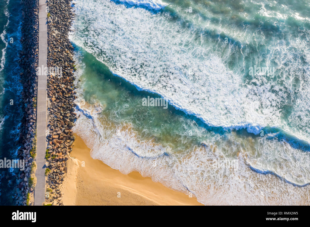A straight down view of the Breakwall at Nobbys Beach - Newcastle Australia with rough surf pounding onto the shoreline. Nobbys BEach - Newcastle - NS Stock Photo