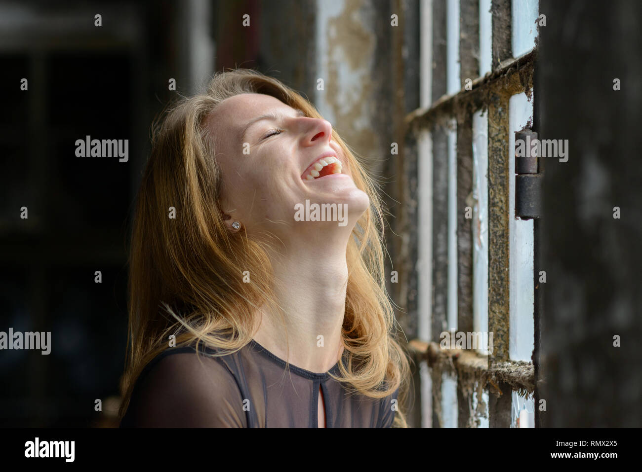 Happy amused young woman enjoying a good laugh with her head thrown