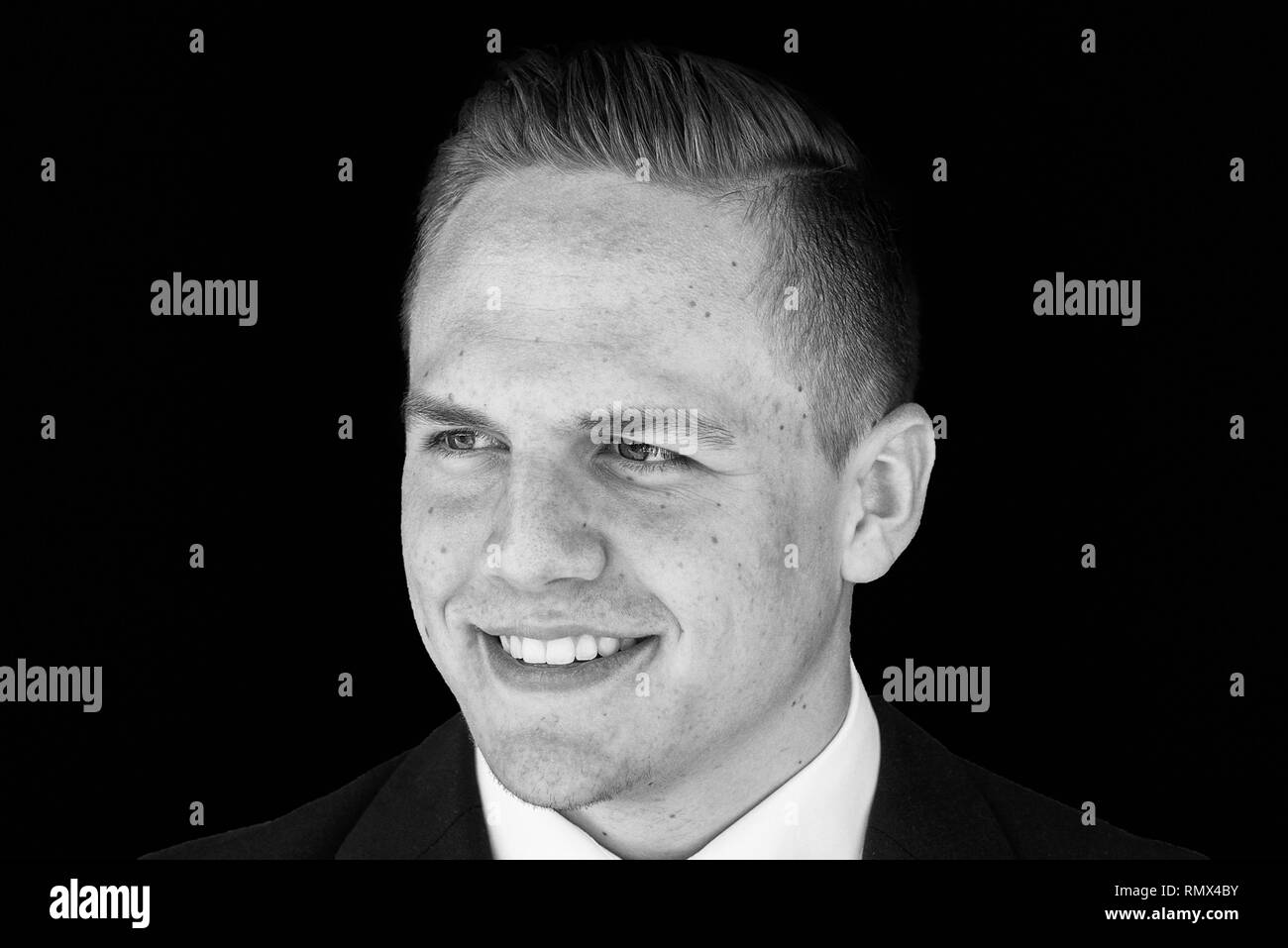 Smiling handsome young businessman in suit and tie looking off to the side with a quiet smile of satisfaction in black and white Stock Photo