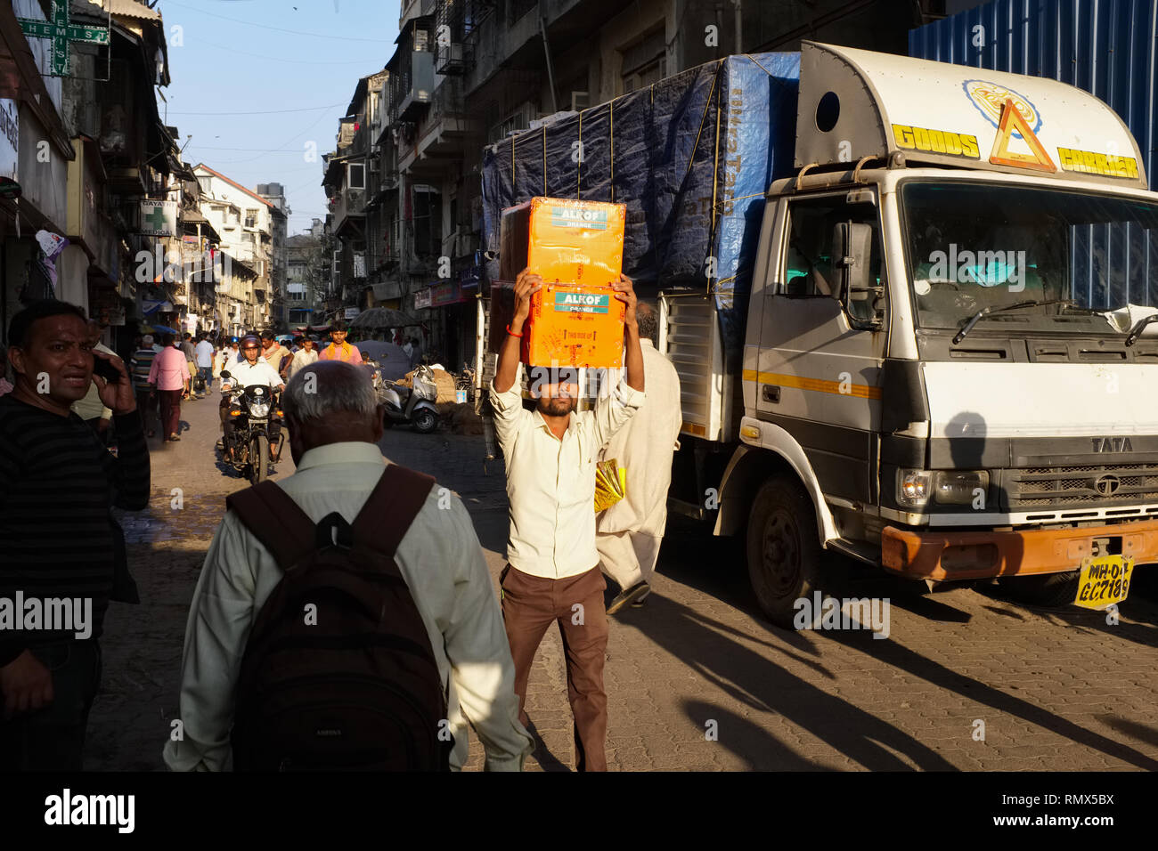 A porter in Kalbadevi Road, Bhuleshwar, Mumbai, India, a migrant from Northern India, carrying boxes on his head Stock Photo