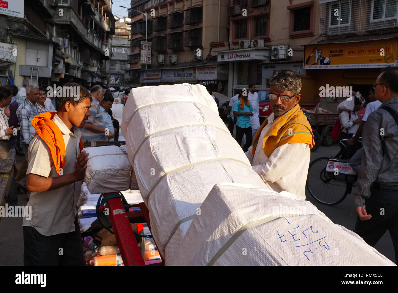 Handcart pullers at Swadeshi Market in Kalbadevi Road, Mumbai, India, migrants from Northern India, preparing cloth bundles for transport Stock Photo