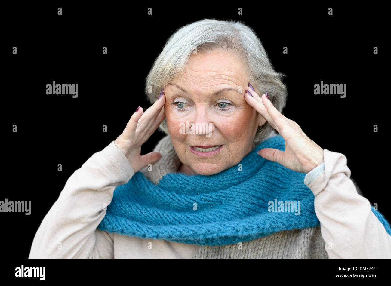Confused and bewildered senior lady holding her hands to her temples as she looks aside, conceptual of the onset of dementia or Alzheimers disease Stock Photo