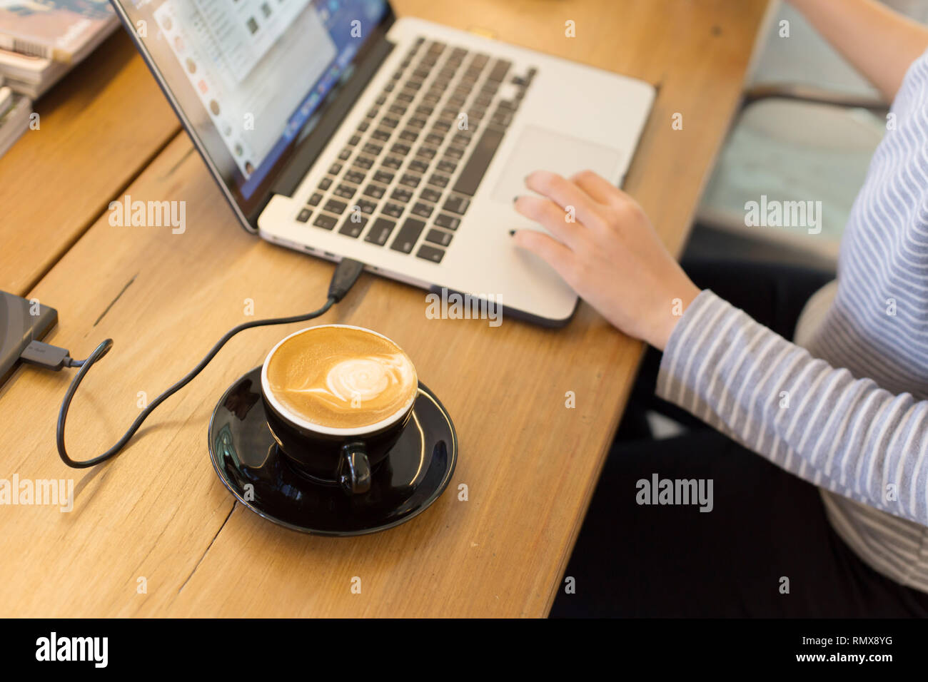 latte coffee with indy girl freelance working in cafe with computer laptop on wooden table. Stock Photo