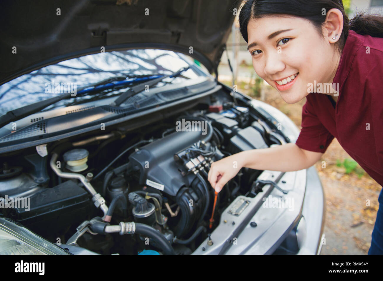 Teen girl open car hood check engine oil level of vehicle before