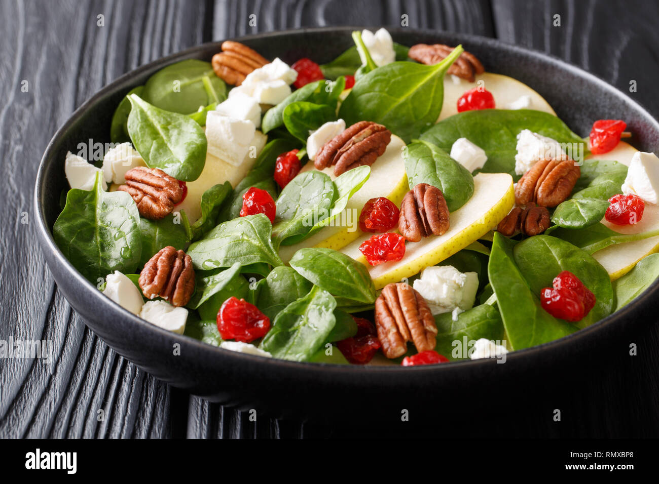 Spicy fruit salad with pears, baby spinach, pecans, feta cheese and cherries closeup on a plate on the table. horizontal Stock Photo
