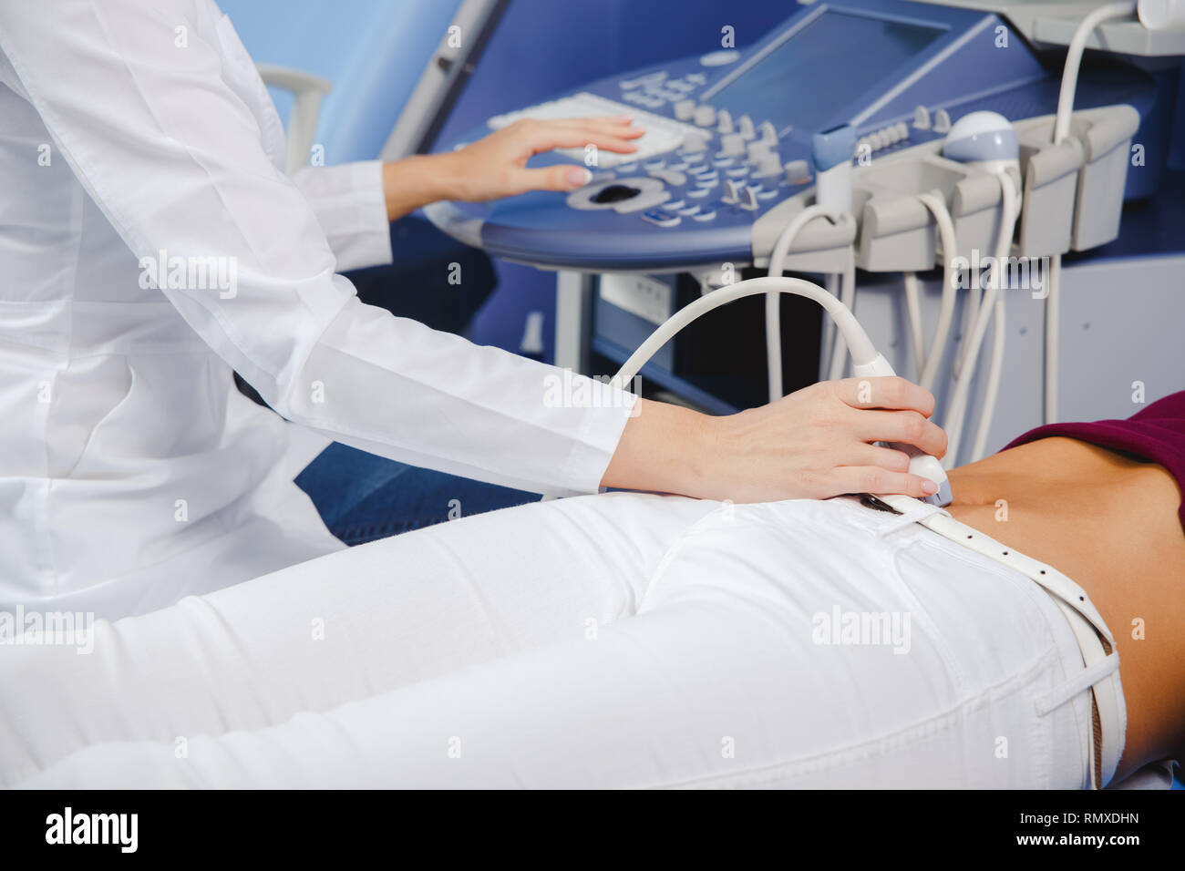 female doctor operating ultrasound scanner examining belly of her