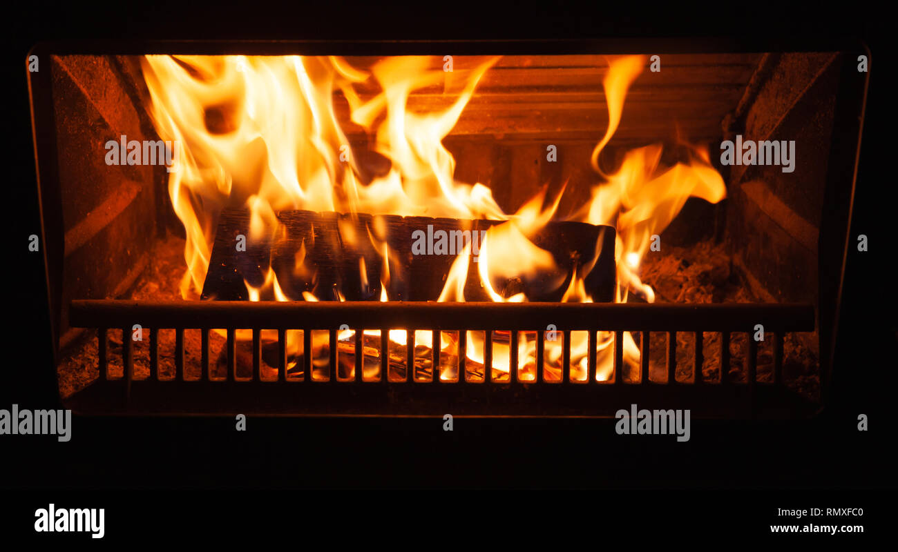 Firewood burns in the fireplace at night, closeup photo Stock Photo