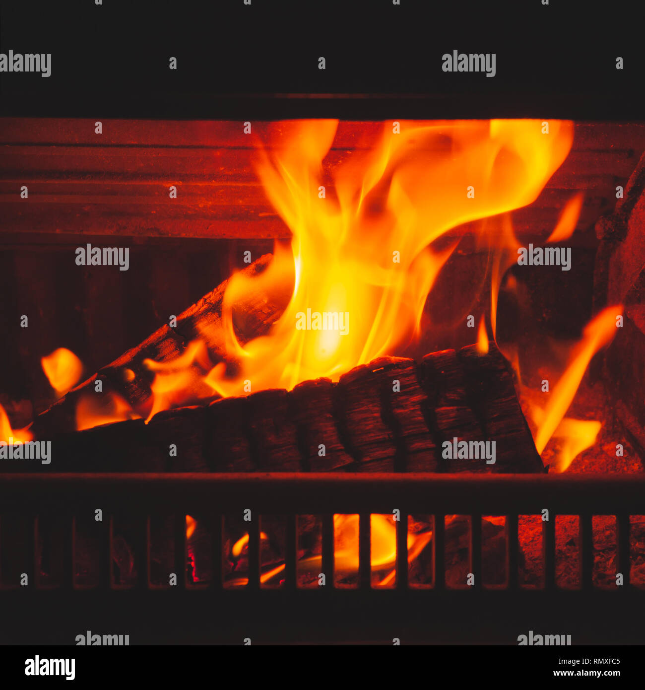 Firewood burns in the fireplace with a bright flame at night, square photo Stock Photo