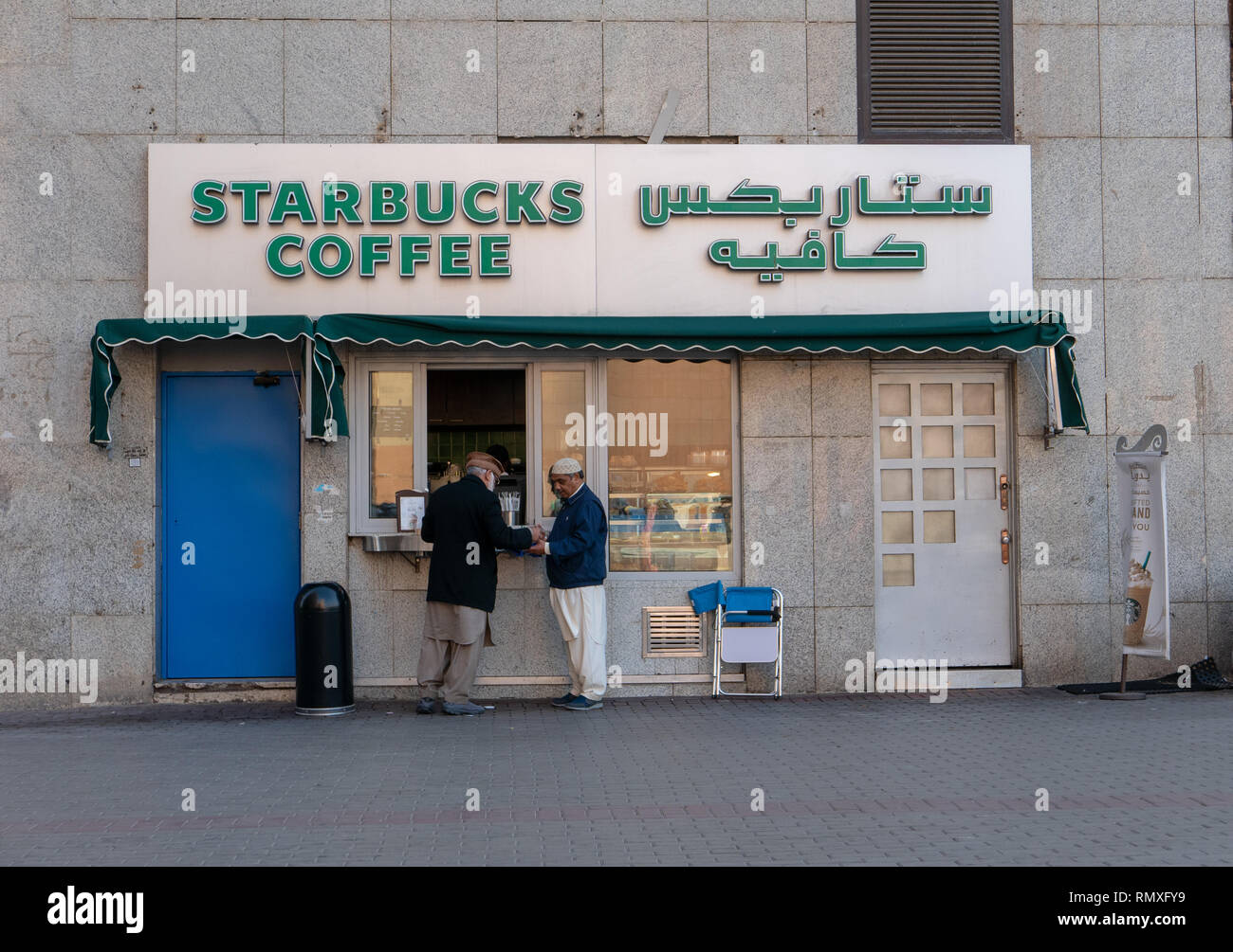 MEDINA, SAUDI ARABIA-CIRCA 2016 : Two Muslim men buy hot drinks at Starbucks Coffee outlet located just outside Nabawi Mosque in Medina, Saudi Arabia. Stock Photo