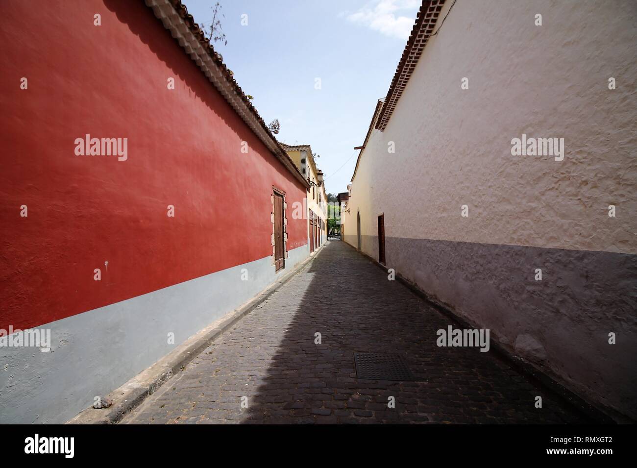 A narrow passageway between red and white walls. Long and narrow street with colored walls. Wide angle shot street on La Laguna, Tenerife. Stock Photo
