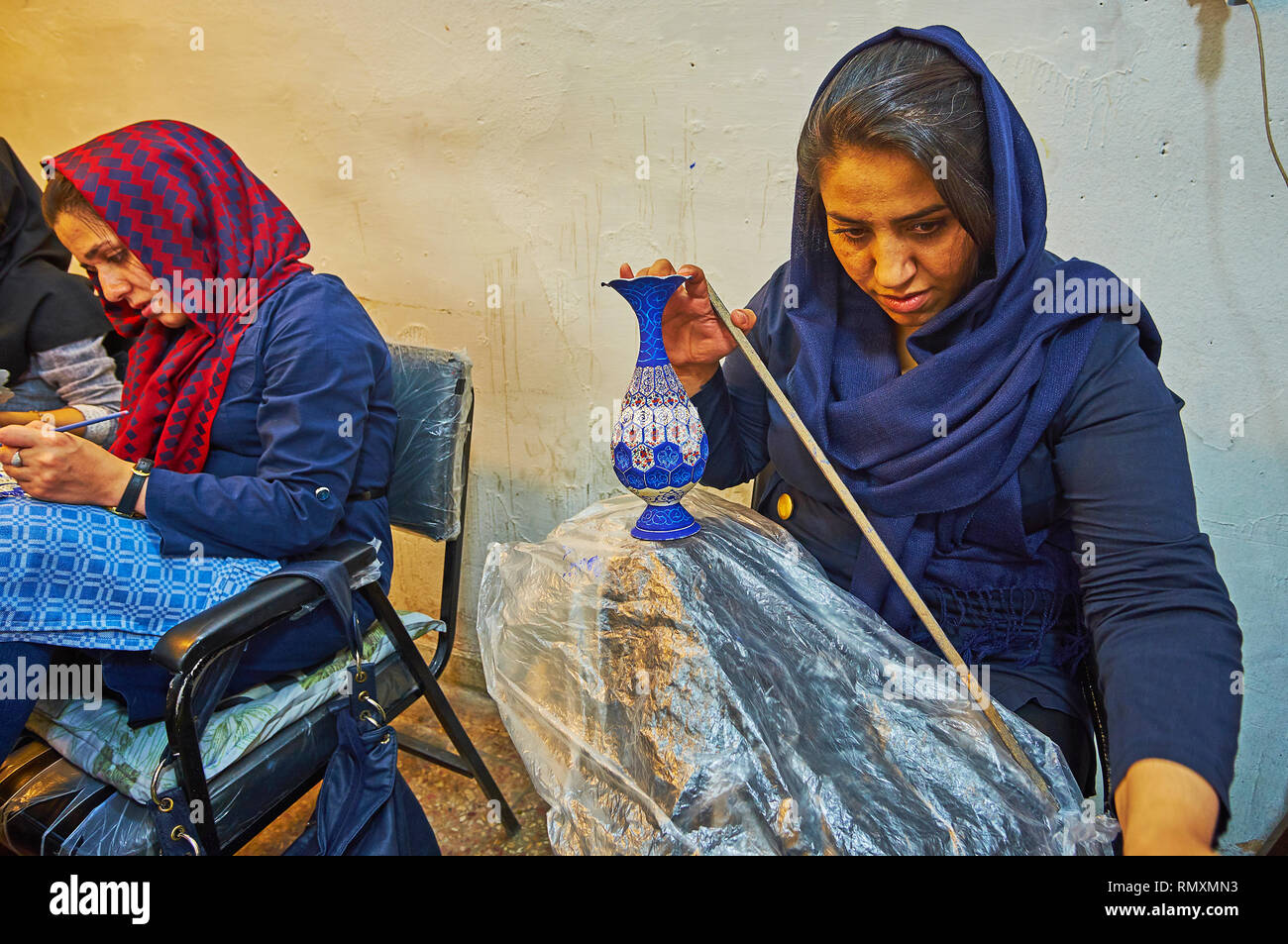 ISFAHAN, IRAN - OCTOBER 21, 2017: The young artisan works in meenakari enamel technique, creating traditional porcelain vase in workshop of Grand Baza Stock Photo