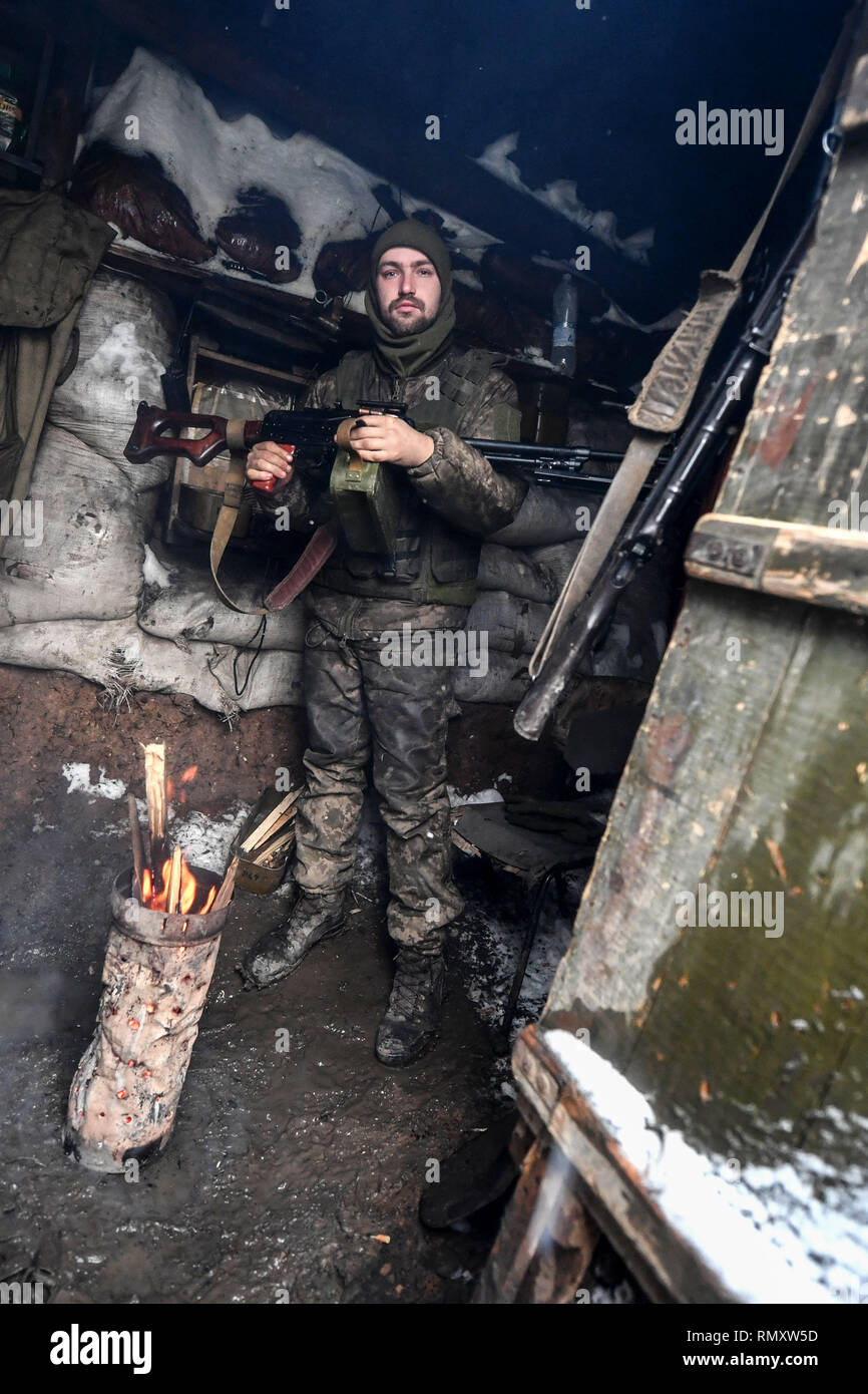 A young Ukrainian soldier seen holding a light machine gun warming himself by a fire. The conflict in the Eastern Ukraine has become more political than physical since 2014 when 12,000 lost their lives. Today though, it is spasmodic and most shelling is during the nighttime. (The official observers from OSCE organization do not monitor at night!). Due to the Minsk ceasefire both parties try to respect it and only light equipment is seen in use. Stock Photo