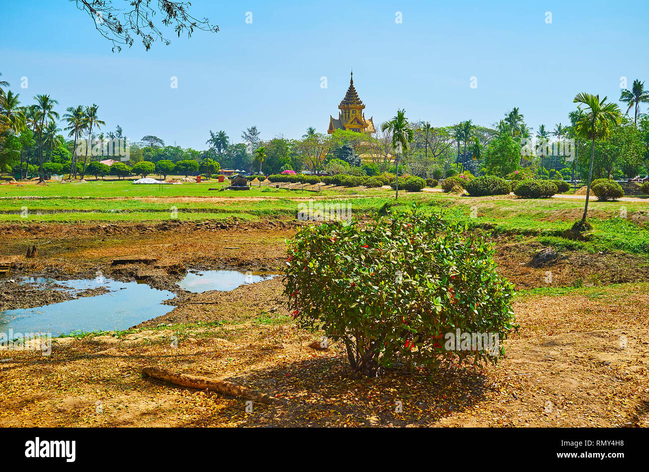 The lush greenery of ornamental tropic garden of Kanbawzathadi palace with a view on the pyatthat (multistaged) roof of Bhammayarthana Throne Hall (Be Stock Photo