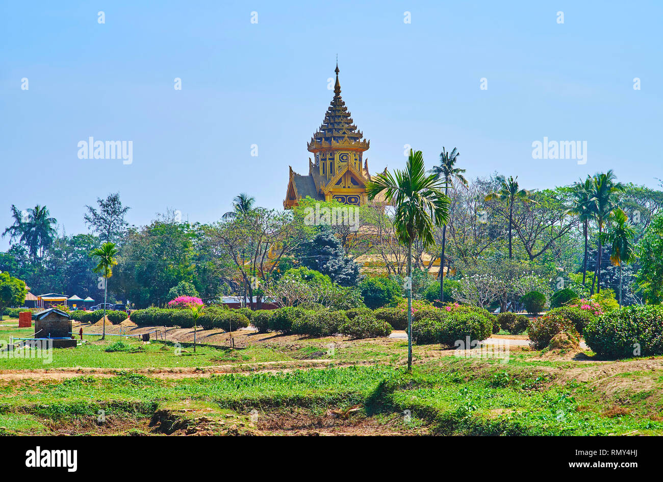 The lush greenery of the Royal garden hides the ornate gilded building of Bhammayarthana Throne Hall (Bee Hall) of Kanbawzathadi palace, Bago (Pegu),  Stock Photo