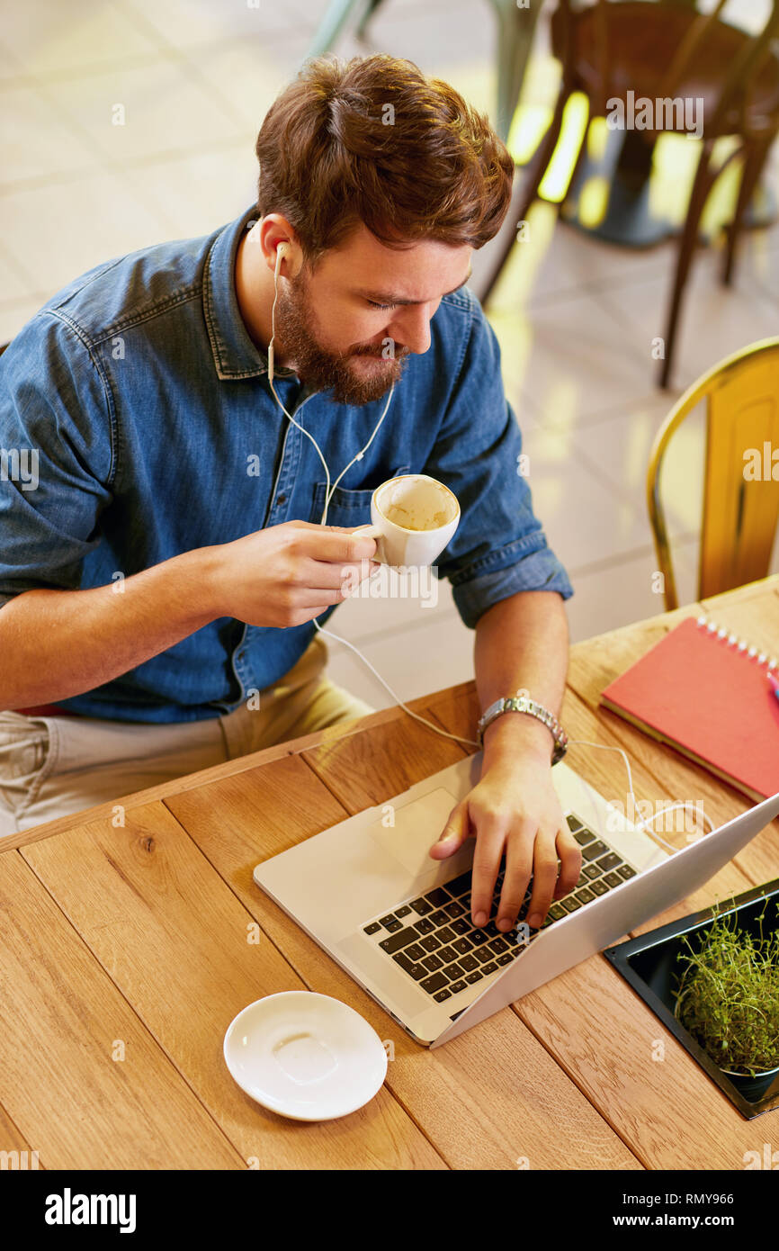 Male working at laptop and drinks coffee in cafe Stock Photo