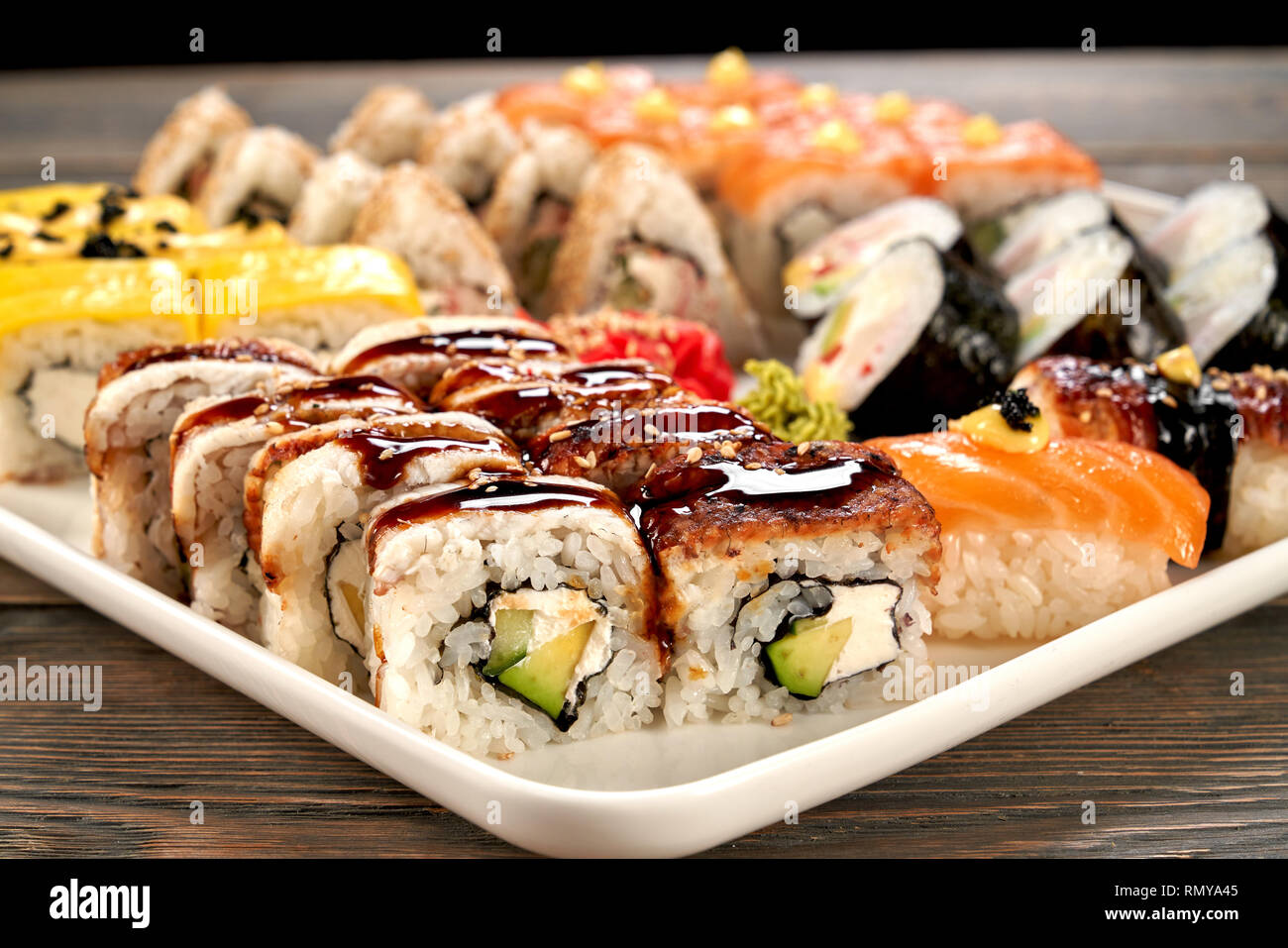 California roll close up. Tasty sushi filled with smoked eel, avocado and cream cheese, unagi sauce topping. Uramaki sushi set. Stock Photo