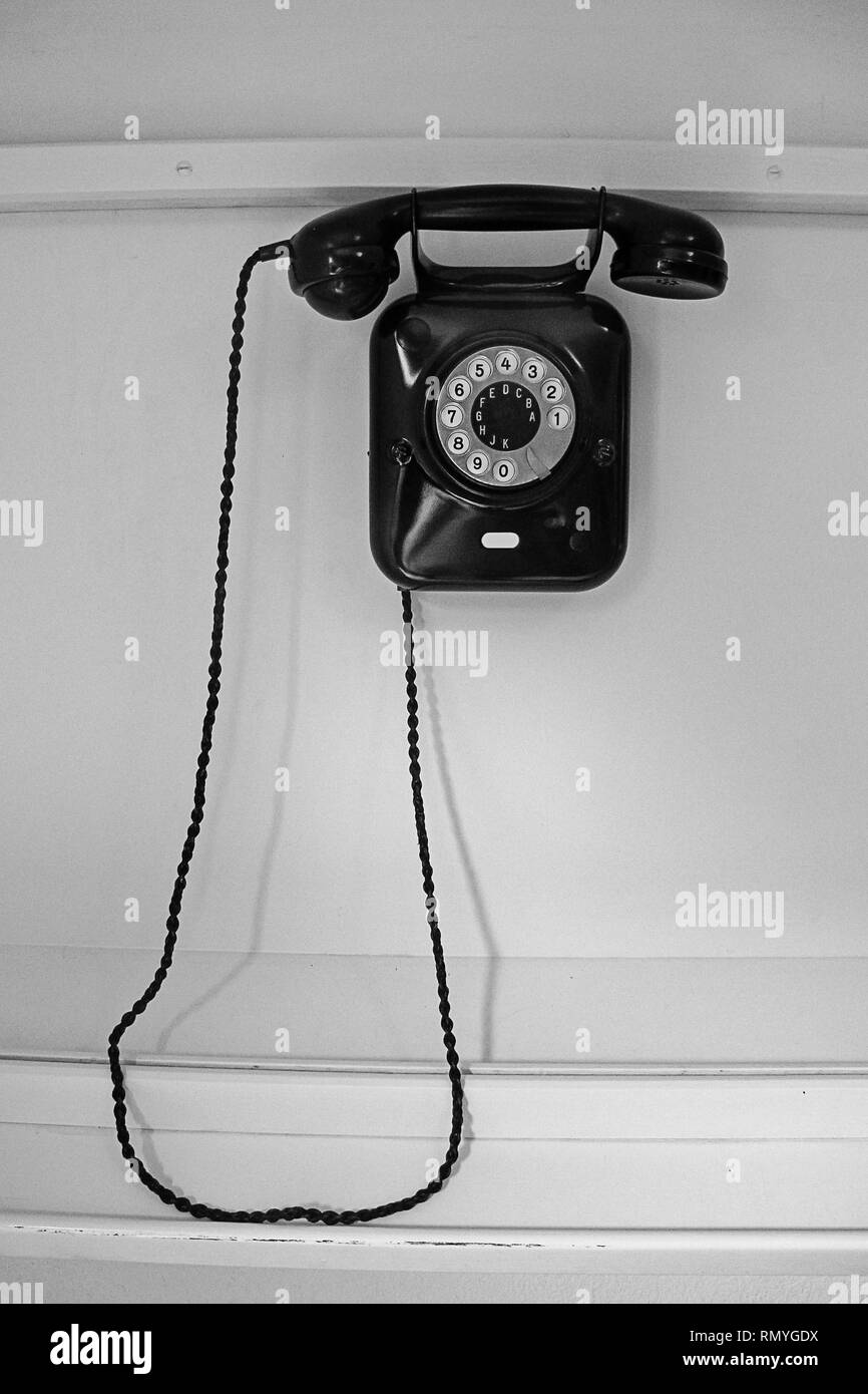 old-fashioned  black telephone hanging on white wall Stock Photo