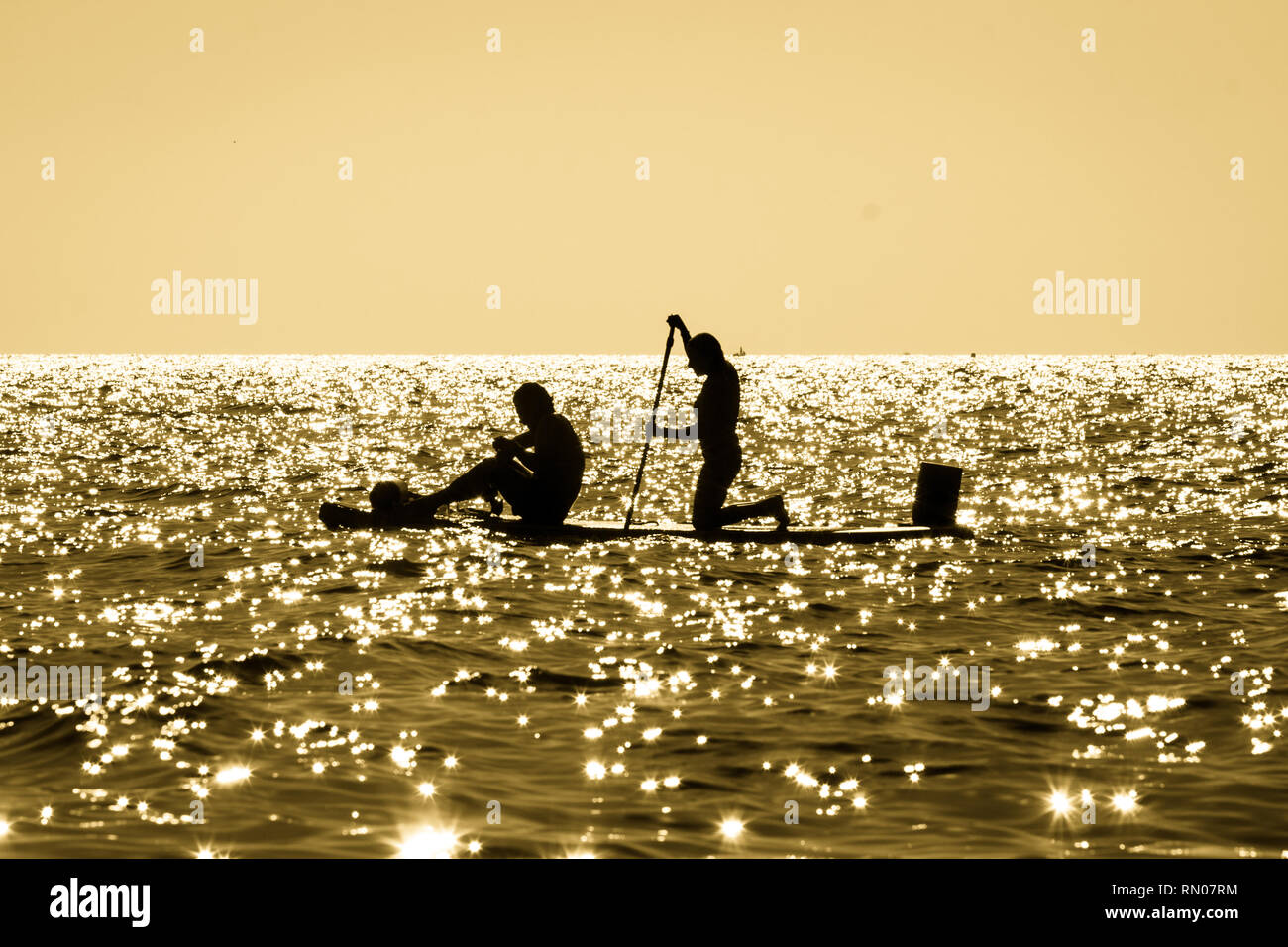 Two Silhouettes Of Men In A Fishing Boat At Sunset Stock Photo