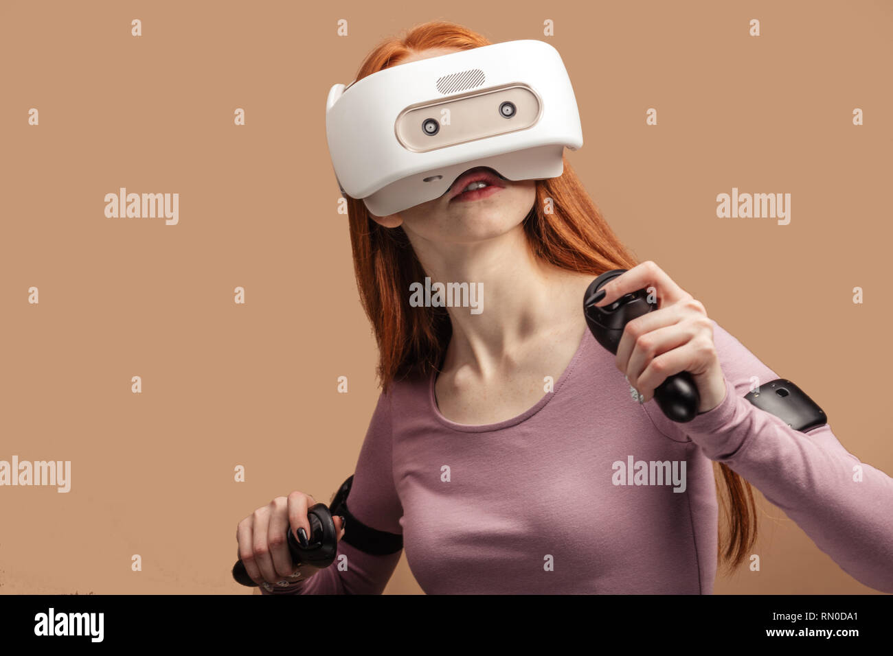 Caucasian attractive girl experiencing vivid impressions , testing virtual  reality helmet, isolated over studio pink background Stock Photo - Alamy