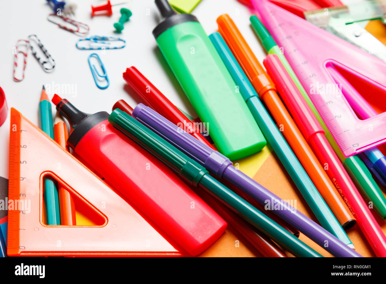 Assorted school supplies, including pens, pencils, scissors, glue and a ruler, on a white