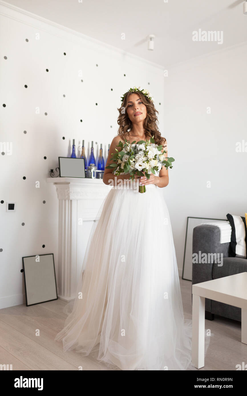 Beautiful bride in elegant white wedding dress and veil with long curly hair  posing indoors  CanStock