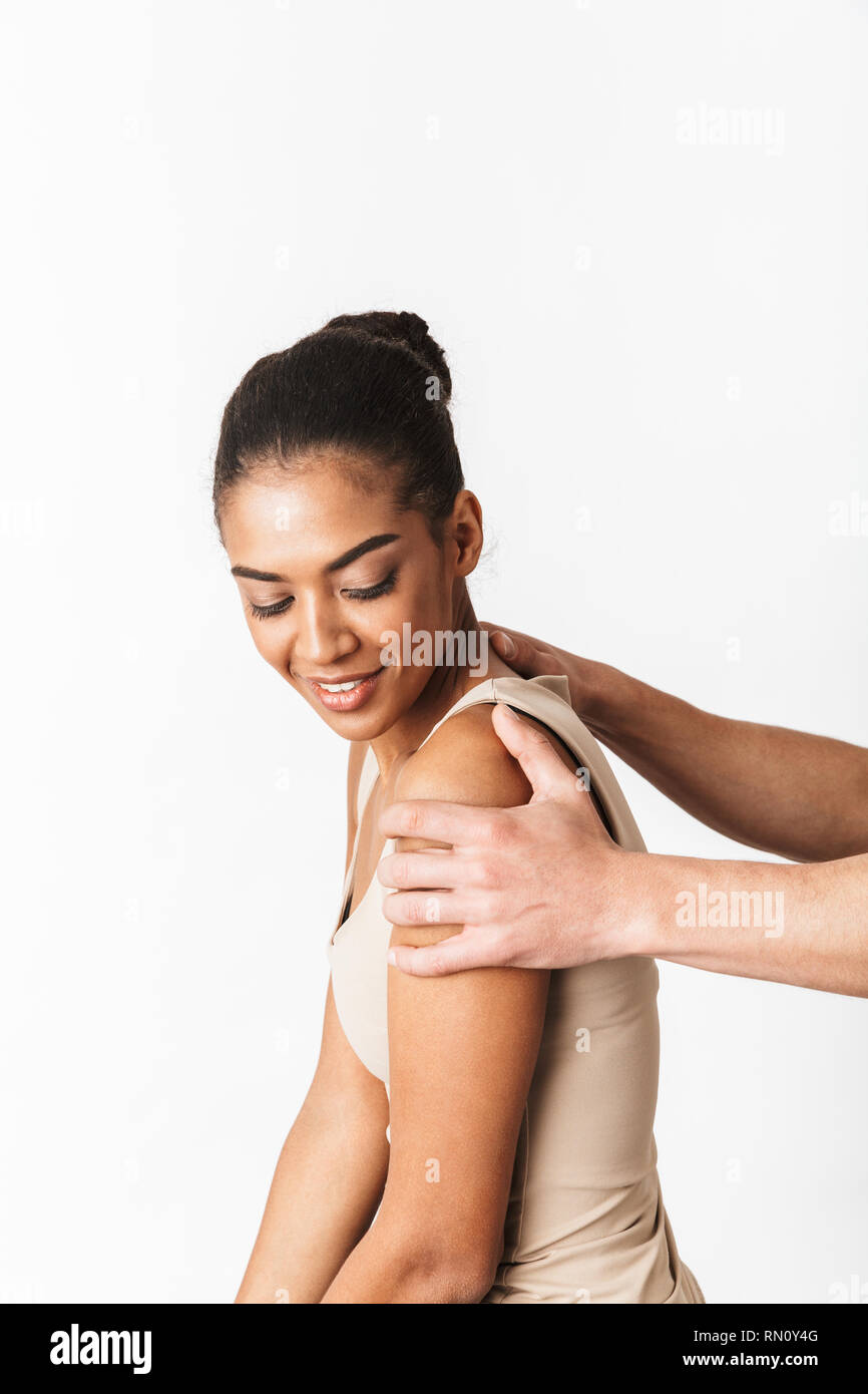 Young african woman sitting while man's hand holding her shoulders isolated over white background Stock Photo