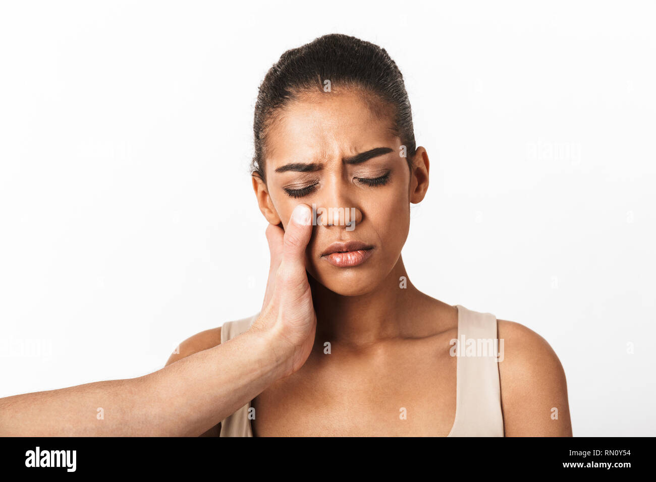 Upset young african woman crying with man's hand on her face isolated over white background Stock Photo