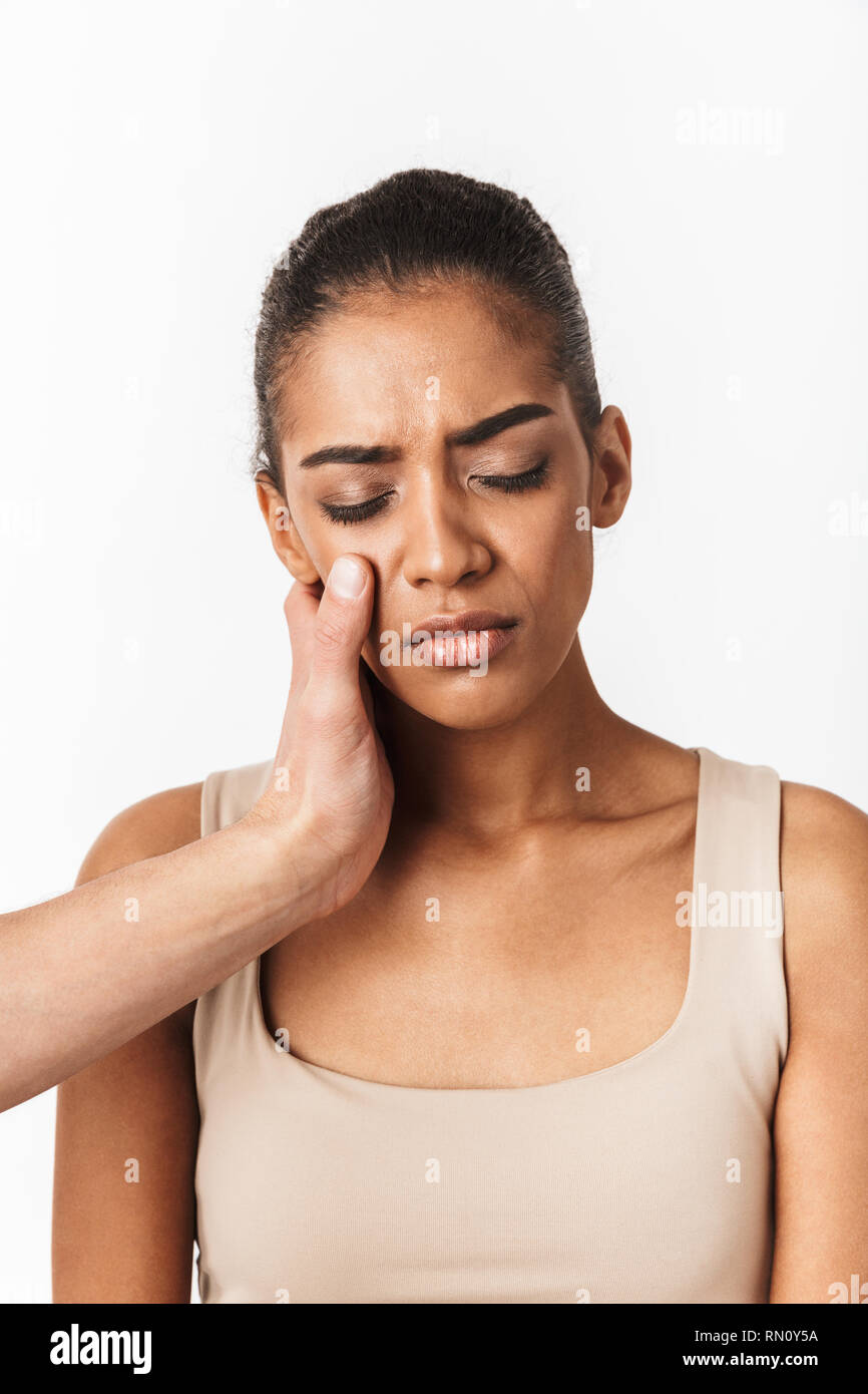 Upset young african woman crying with man's hand on her face isolated over white background Stock Photo