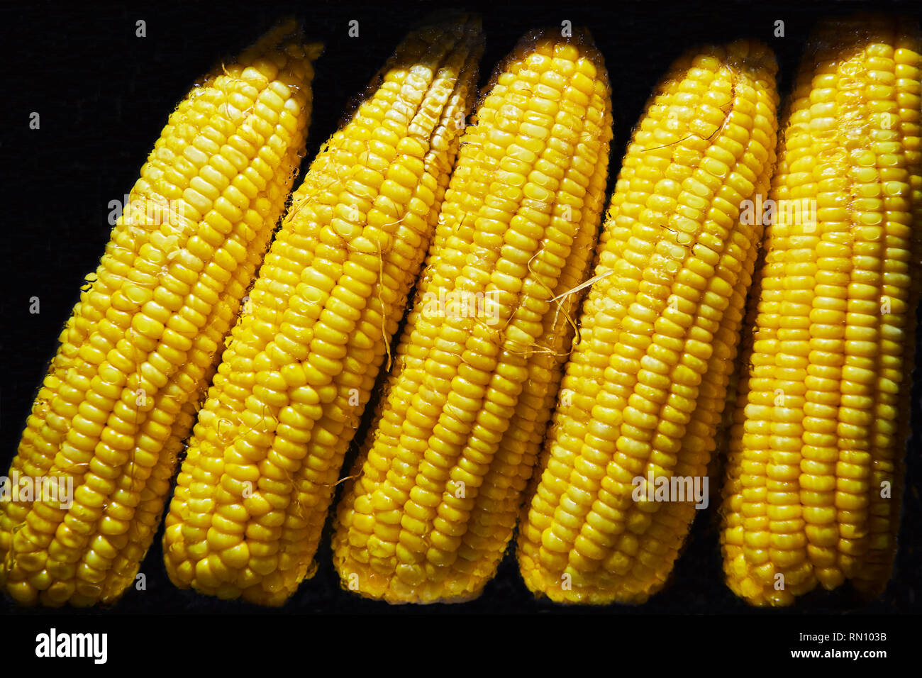 Close-up of ripe boiled yellow corn for sale inside a glass vitrine against a black background, seen on Boracay, Philippines Stock Photo