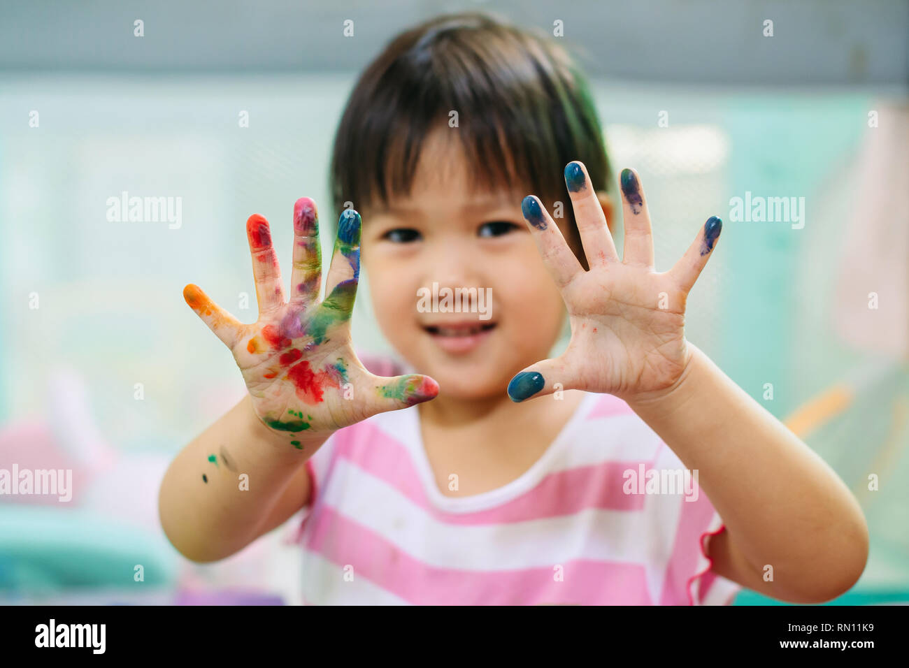 Happy and cute girl uses the hands and fingers for finger painting art work. Picture for concept of school, art subject and play. Stock Photo