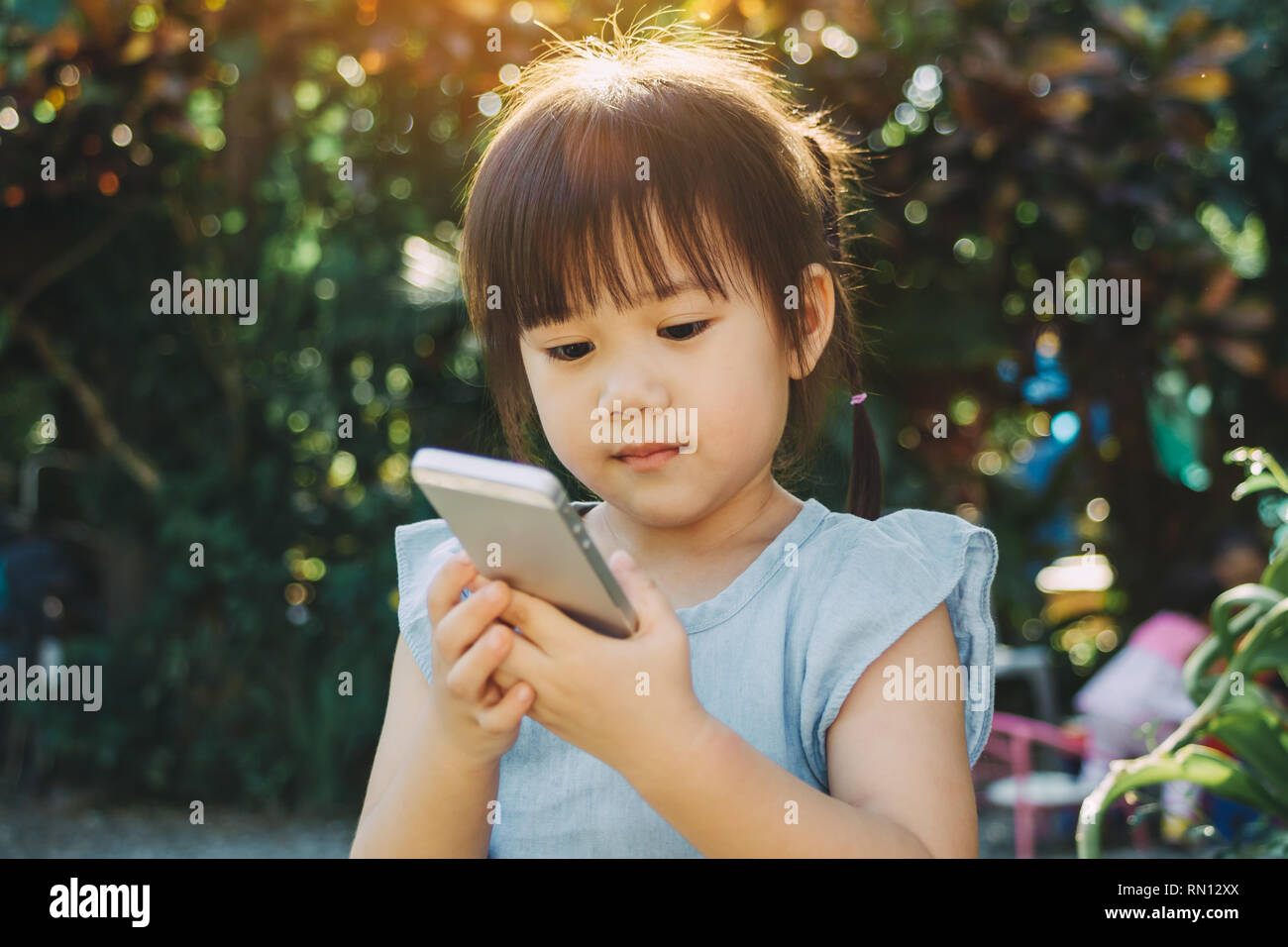 Kids using smart phone : Some research says entertainment media (including TV) be avoided for infants and children Stock Photo
