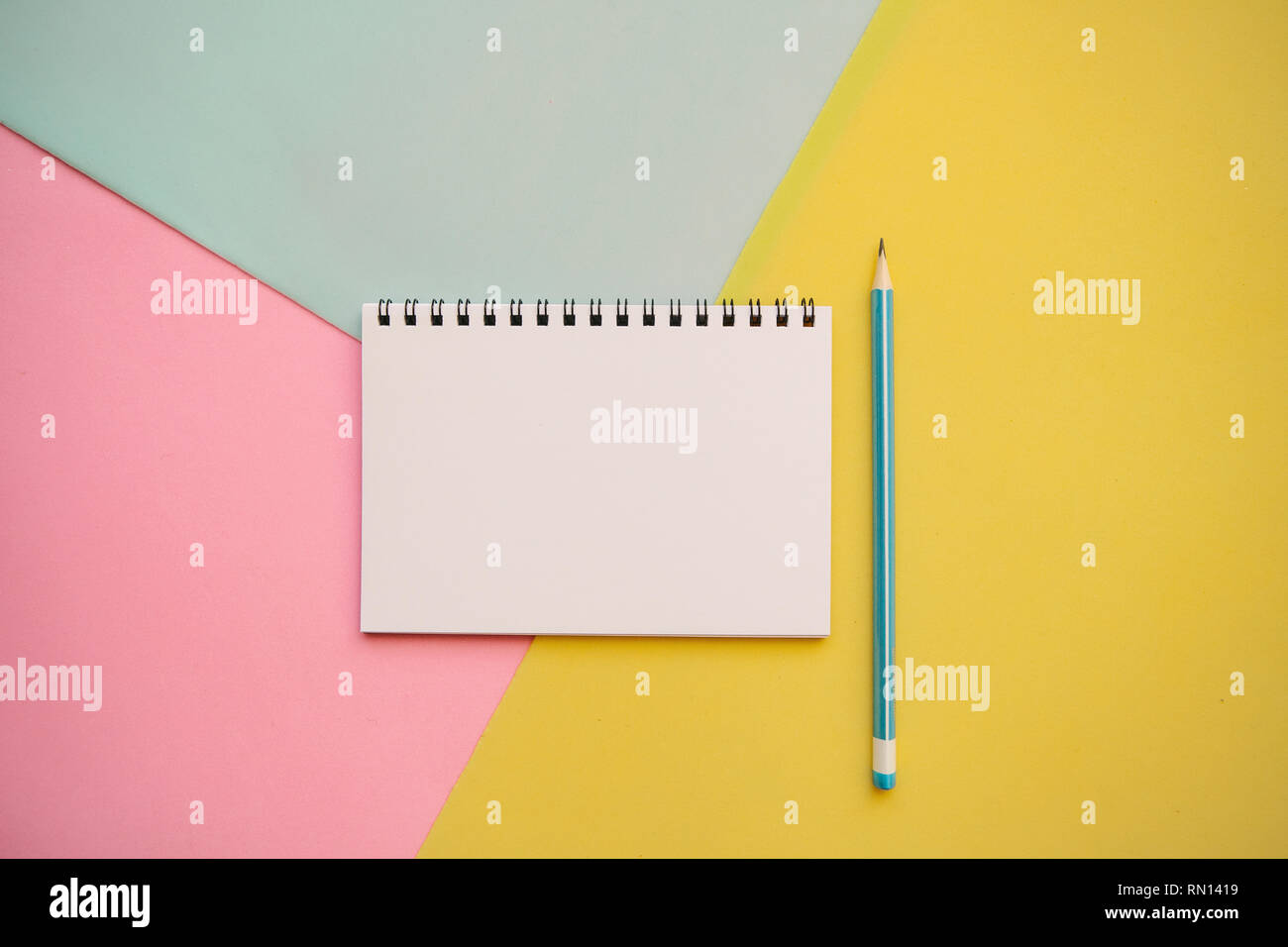 Blank notepad with place for text and a pencil on a multi-colored background. Stock Photo