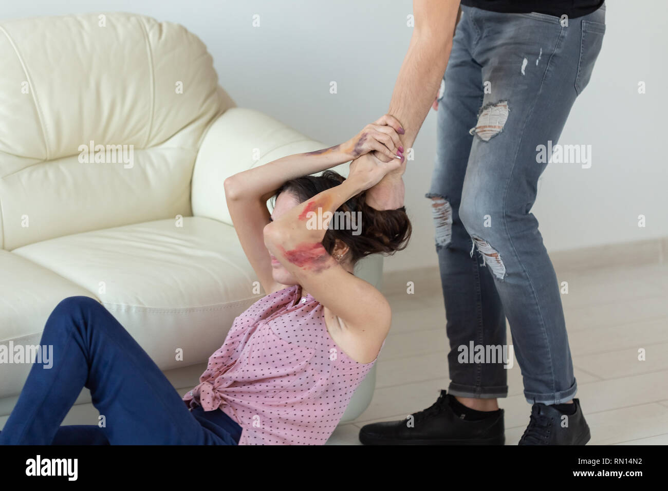 domestic violence, victim and abuse concept - cruel aggressive man grabbing woman lying on the floor Stock Photo