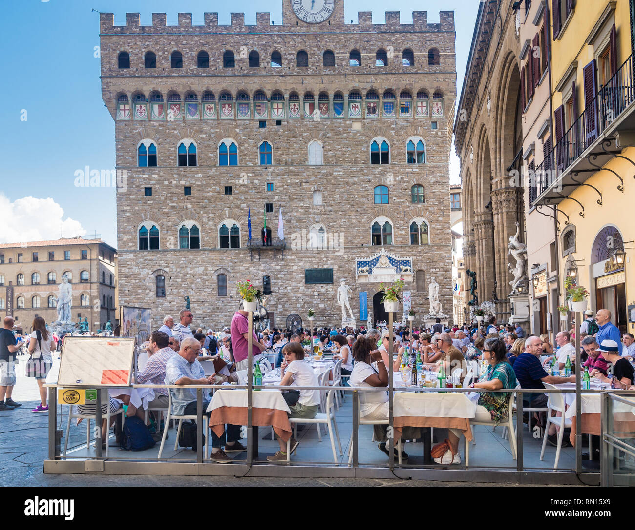 Street restaurant in Piazza della Signoria, Palazzo Vecchio and a replica statue of David in the background. Florence Stock Photo