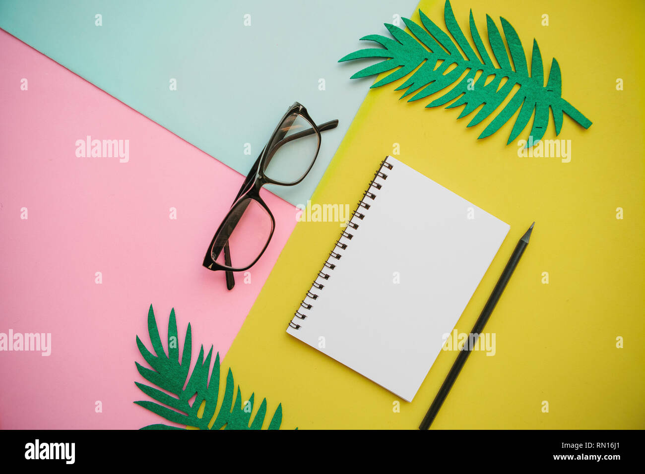 Notepad, glasses and a pencil on a multi-colored background. Stock Photo