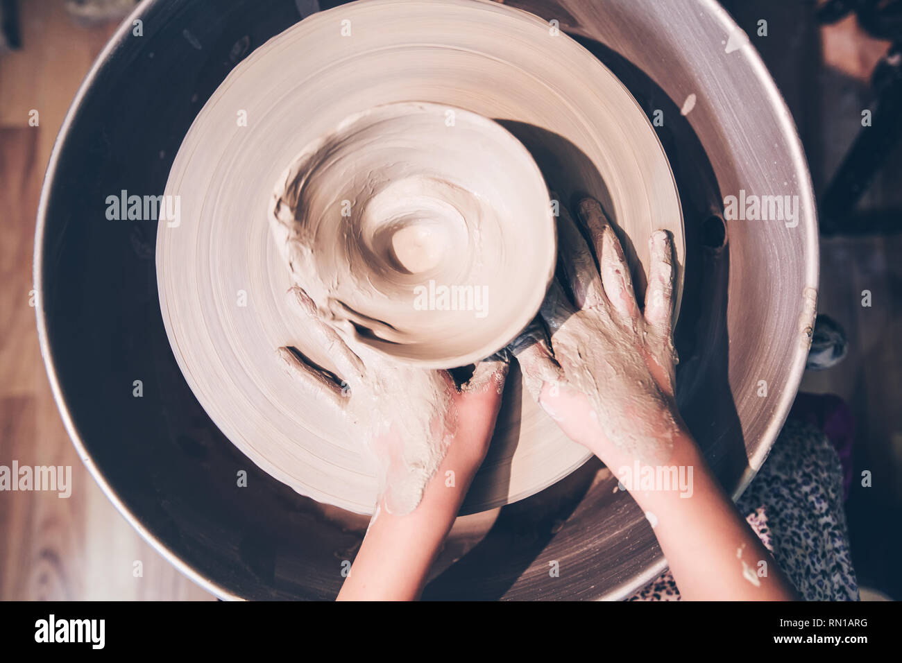 Top view of young potter hands forming ceramic vase with clay on