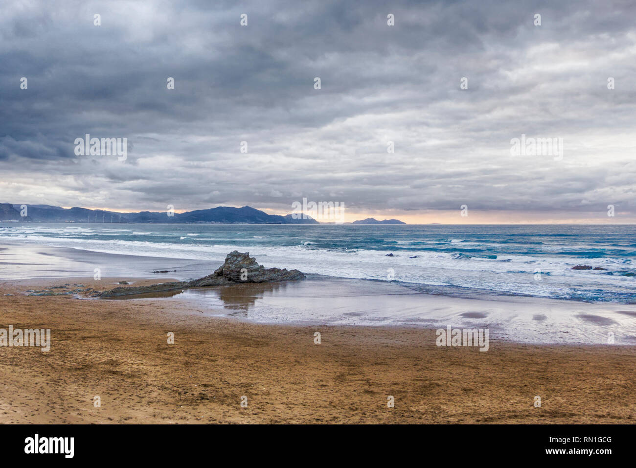 Stormy sky at the Arrietara beach, in Sopela, Basque Country, Spain. With the rock Peña Txuri dominating the image Stock Photo