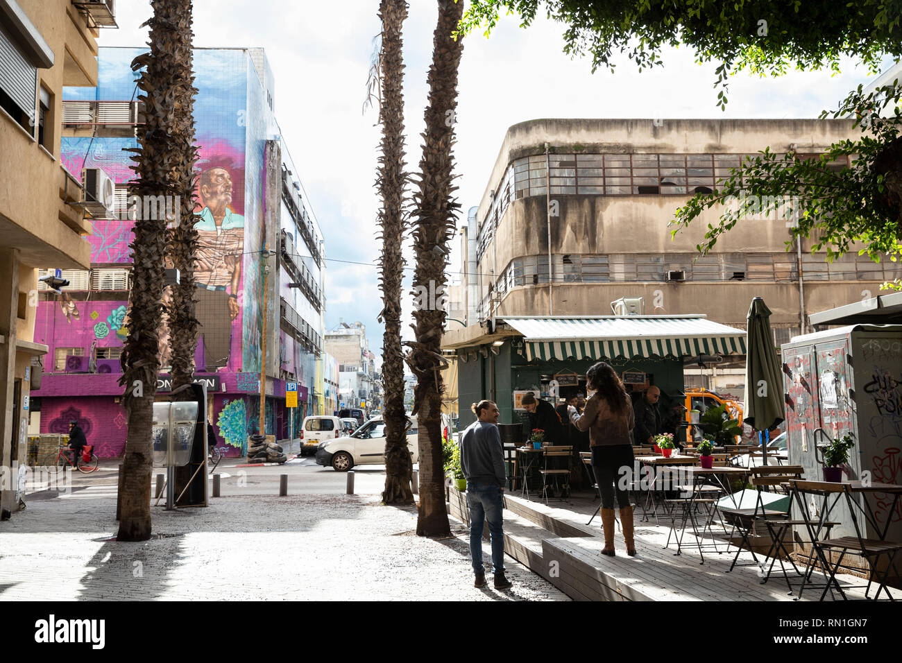 Tel Aviv-Yafo, Tel Aviv, Florentin, Israel - December 28, 2018: Lifestyle street scene - people at caffe shop, old buildings and beautiful mural art Stock Photo