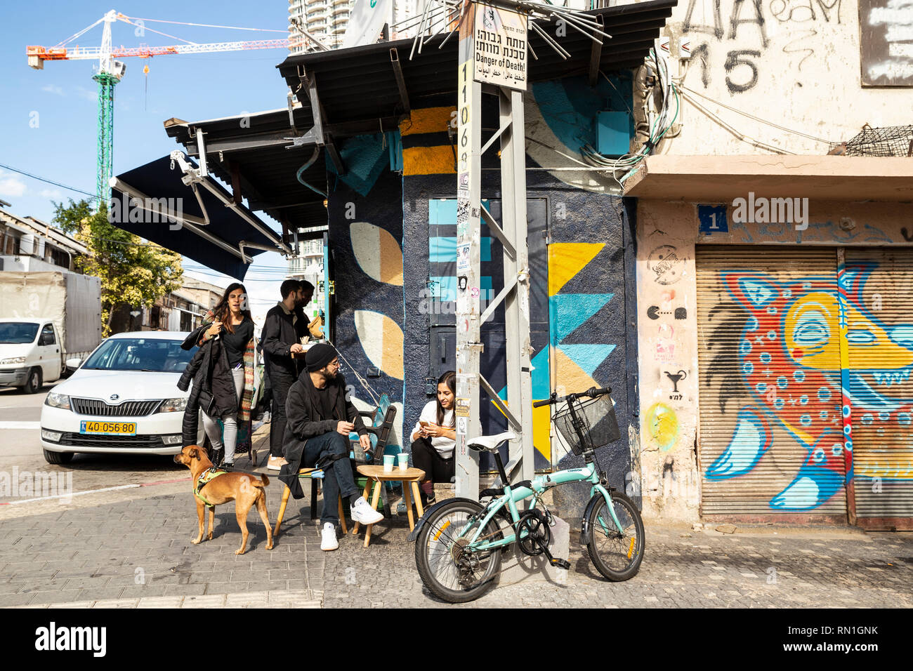 Tel Aviv-Yafo, Tel Aviv, Israel - December 28, 2018: Young Israeli people with a dog and bike, chatting and relaxing in caffe shop, Florentin district Stock Photo