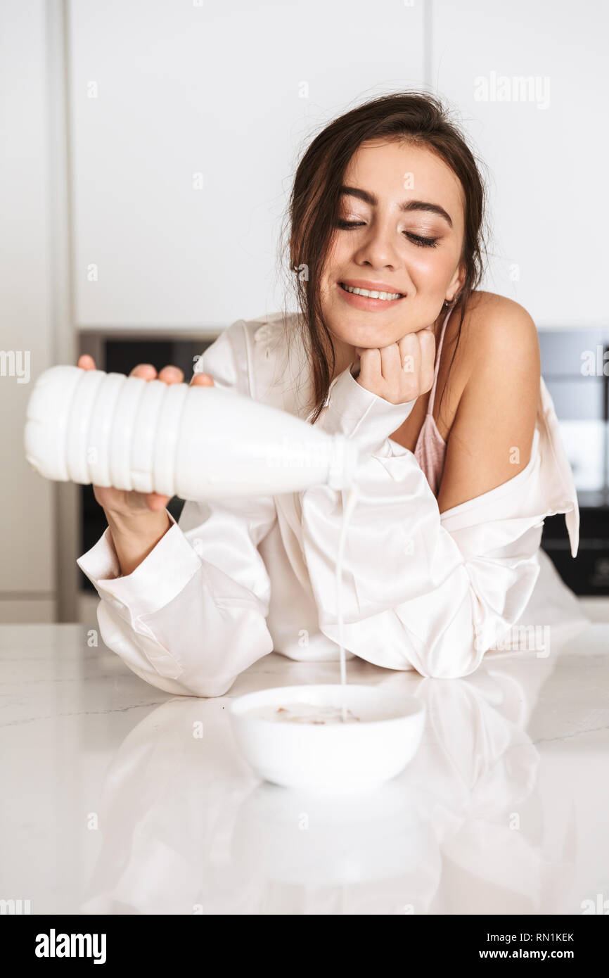 Photo of woman 30s wearing silk clothing eating granola with