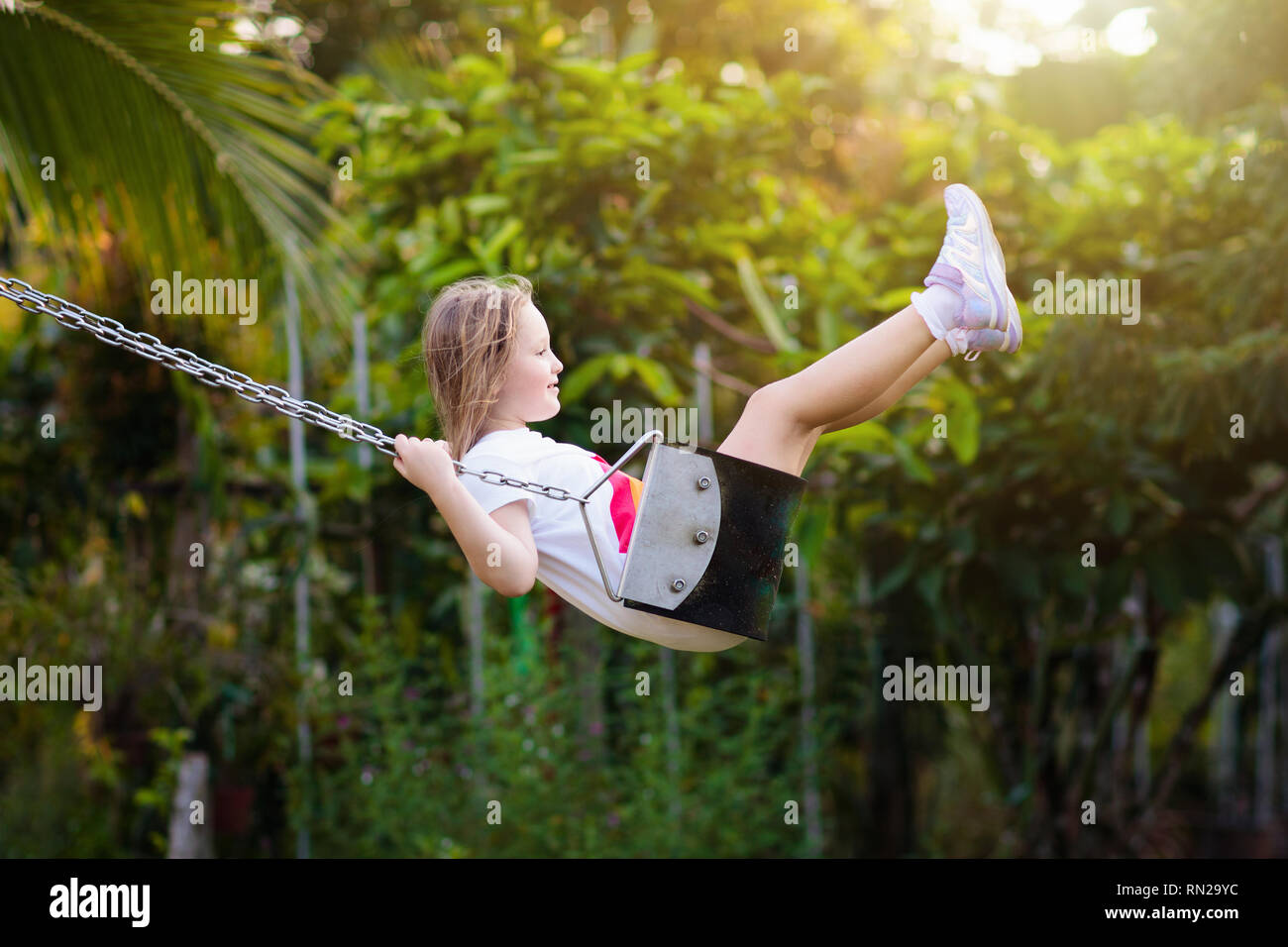 Child swinging on playground on sunny summer day in a park. Kids swing