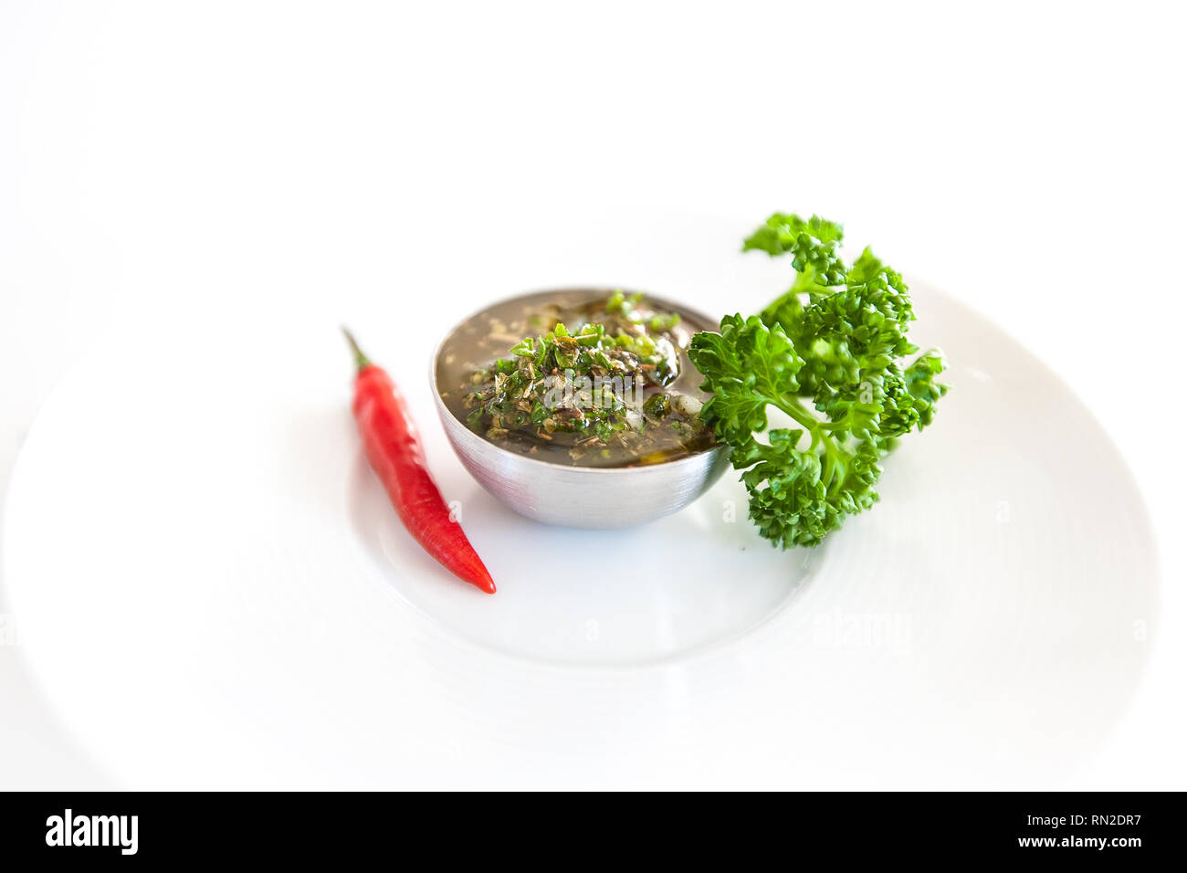 Raw homemade Argentinian green Chimichurri salsa or sauce isolated on a white background Stock Photo