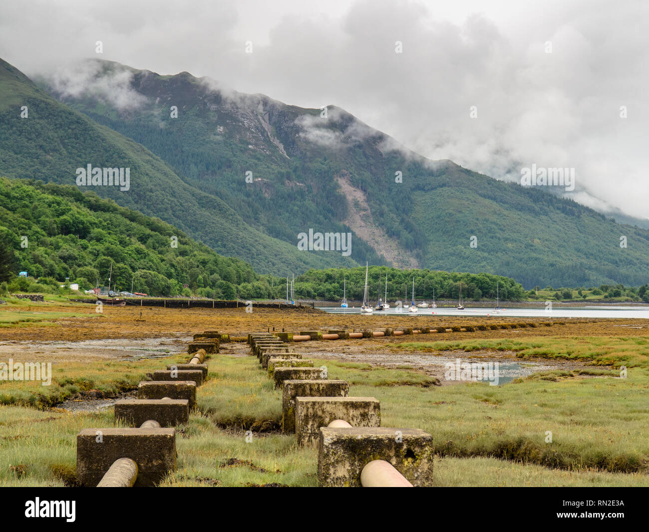 Pipes run across salt marsh into Loch Leven at Glen Coe in the west Highlands of Scotland. Stock Photo