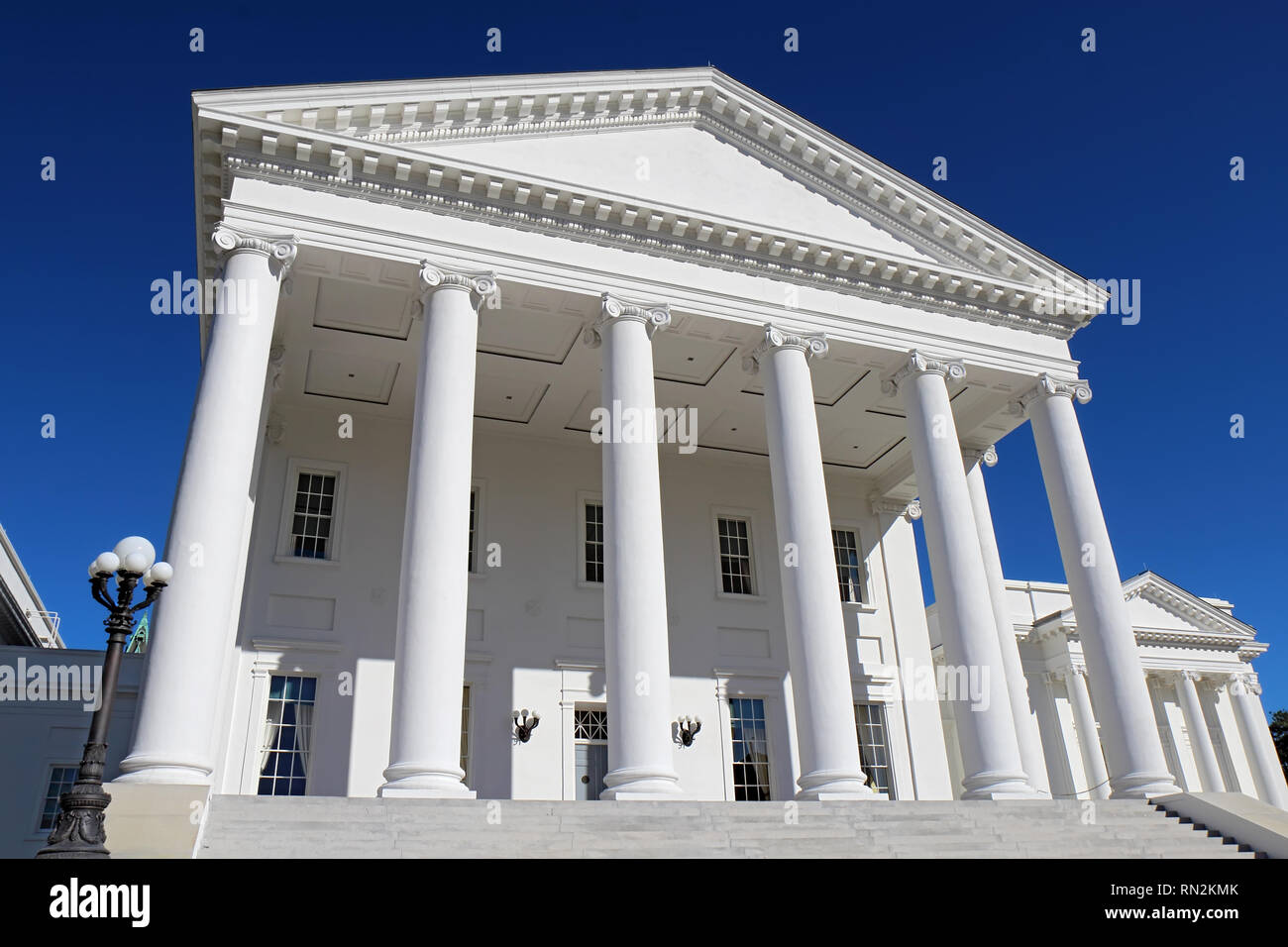 Front facade and columns of the neoclassical Virginia State Capitol building in Richmond against a bright blue sky Stock Photo