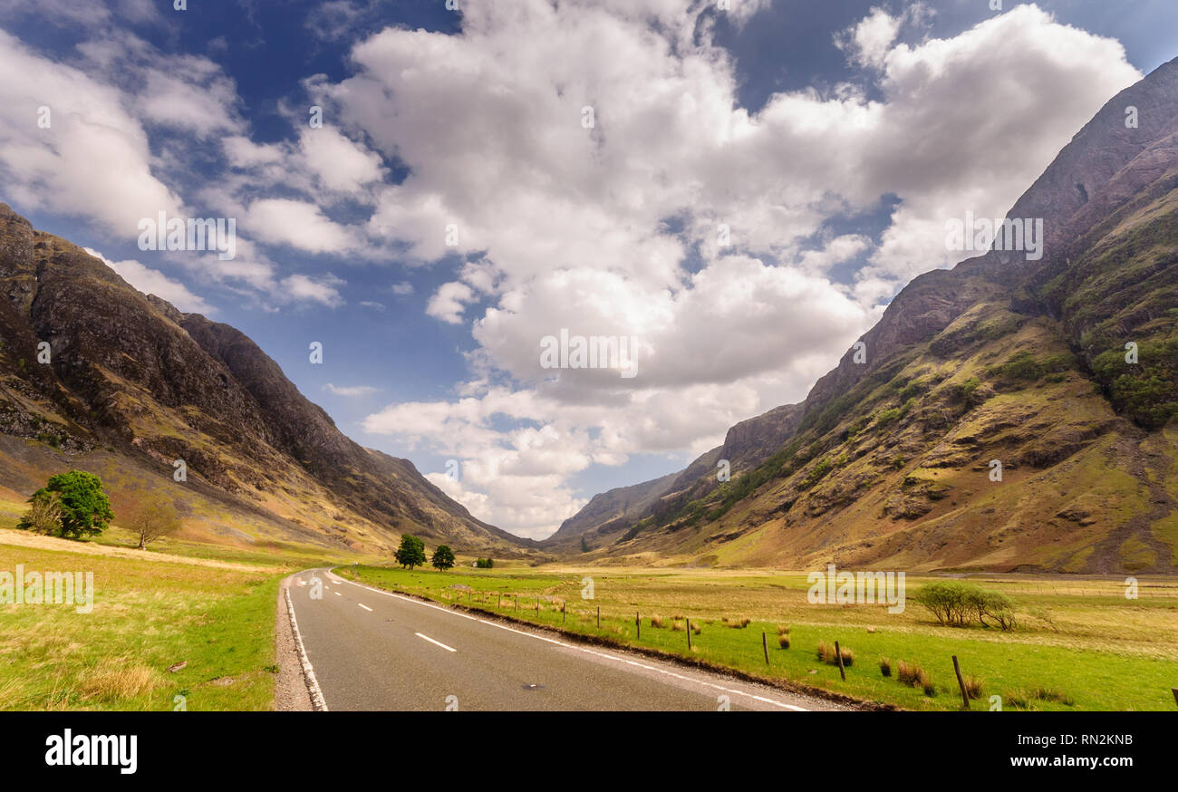 The A82 road crosses pasture fields in the valley floor of Glen Coe, under the mountains of the West Highlands of Scotland. Stock Photo